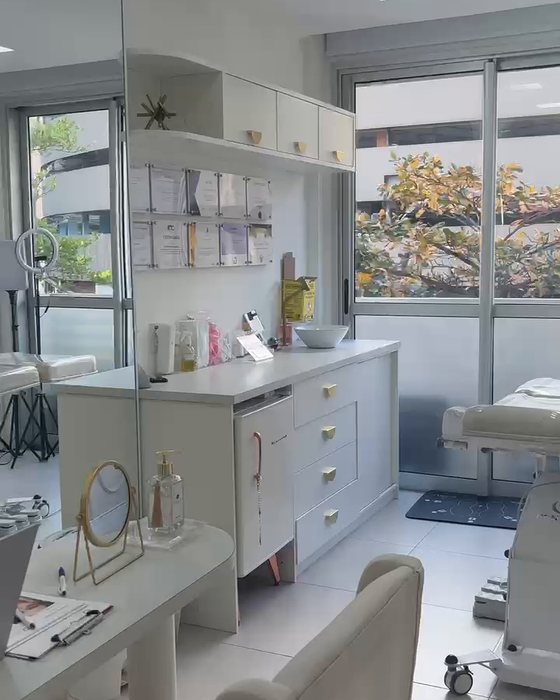 Sala de atendimento clara, com maca, iluminação profissional e janela ampla.