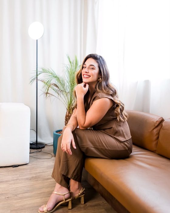 Dra. Luíse Ferrão sentada em um ambiente de recepção com luz natural.