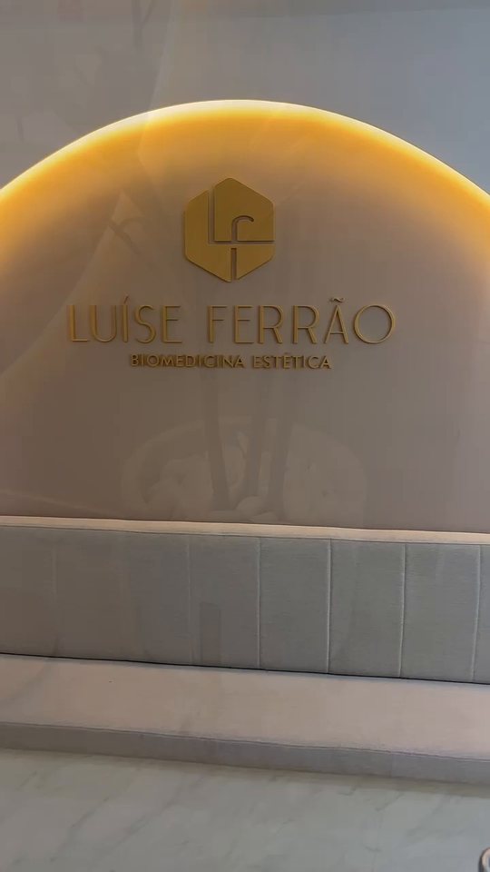 Entrada da clínica com o logotipo em dourado — abrir tour em vídeo.